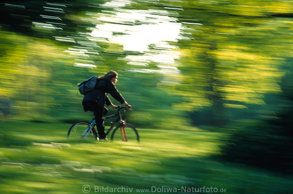 Cyclist speed-drive in blurred green-leaves bicycle-girl spring art-photo dynamic movement fuzziness picture
